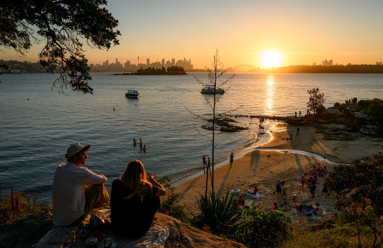 Nj&euml; pamje e Milk Beach n&euml; per&euml;ndim t&euml; diellit, duke par&euml; prapa drejt qendr&euml;s s&euml; Sydney-t dhe Ur&euml;s s&euml;...