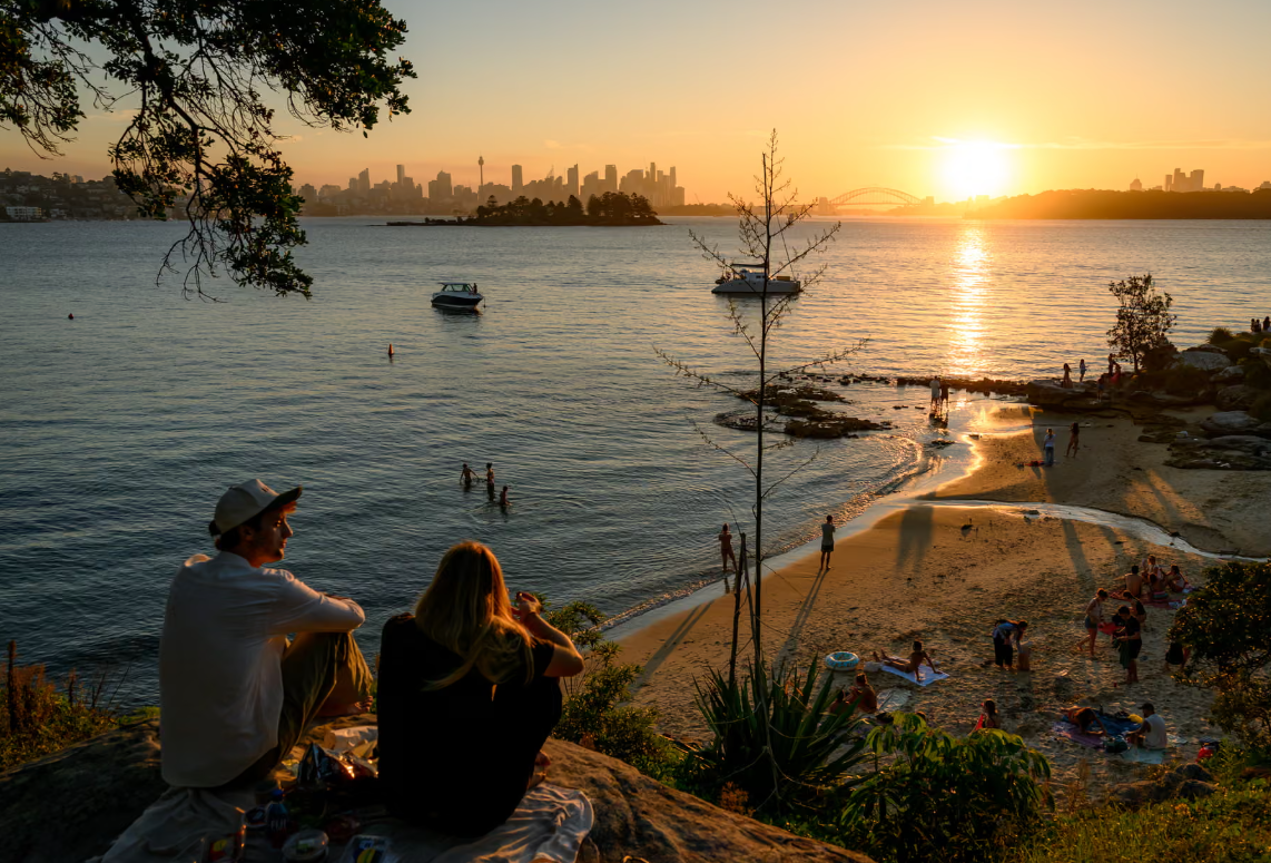 Sydney, Australi: Nj&euml; pamje e Milk Beach n&euml; per&euml;ndim t&euml; diellit, duke par&euml; prapa drejt qendr&euml;s s&euml; Sydney-t dhe...